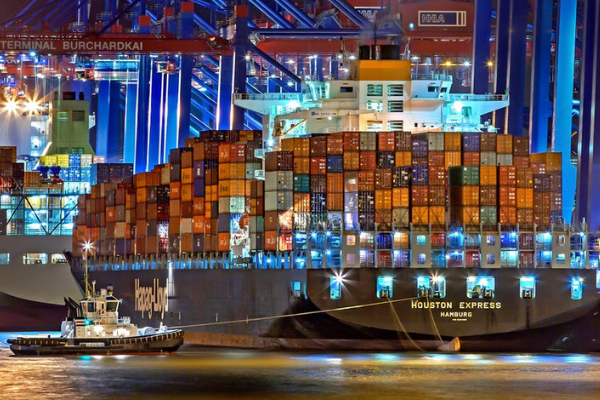 A tugboat pulls a large cargo ship into port