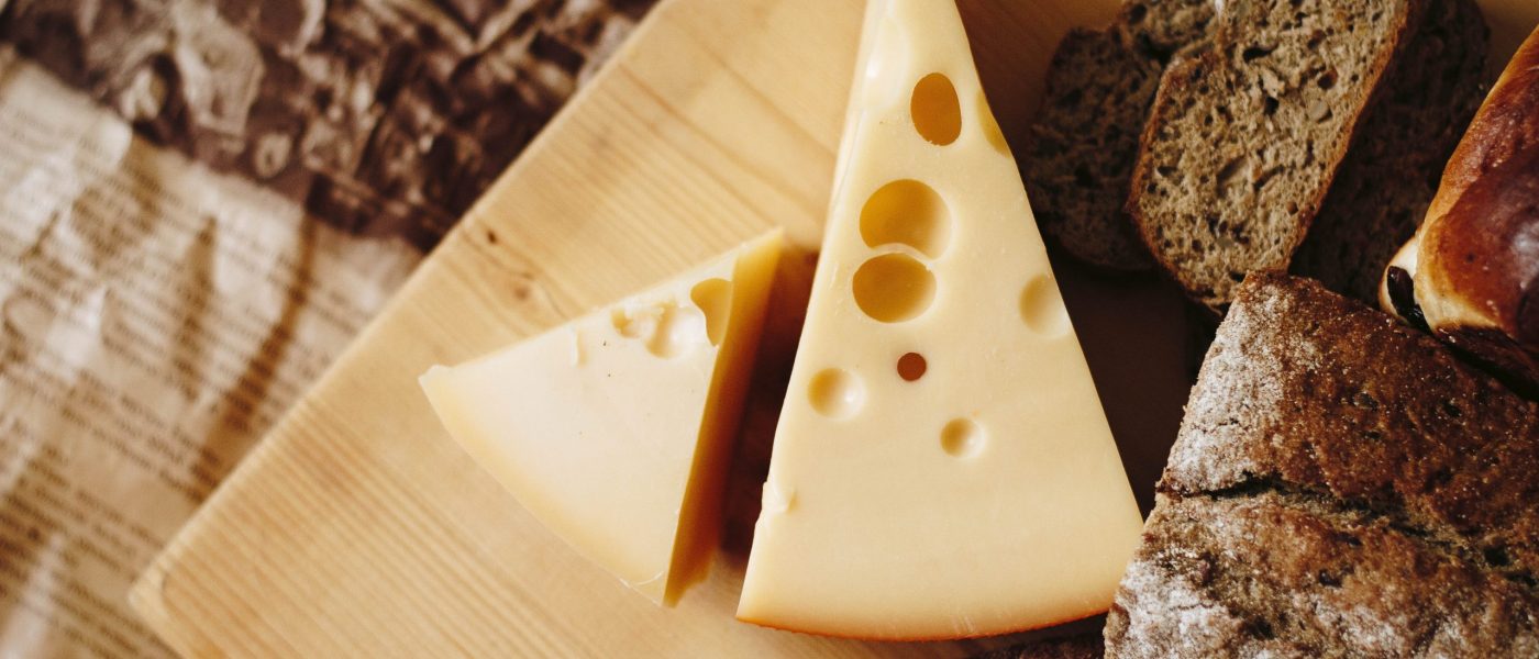 Wedges of swiss cheese on a wooden board - large