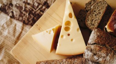 Wedges of swiss cheese on a wooden board - large