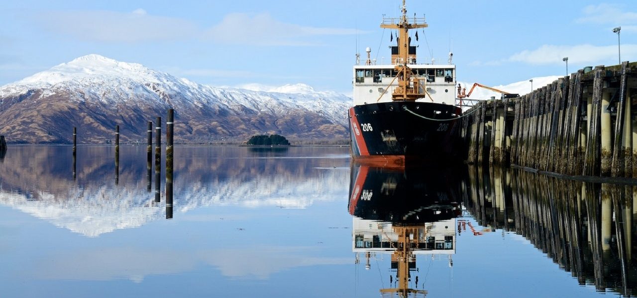 boat docked in front of a snow capped mountain A ship docked in front of a snow capped mountain