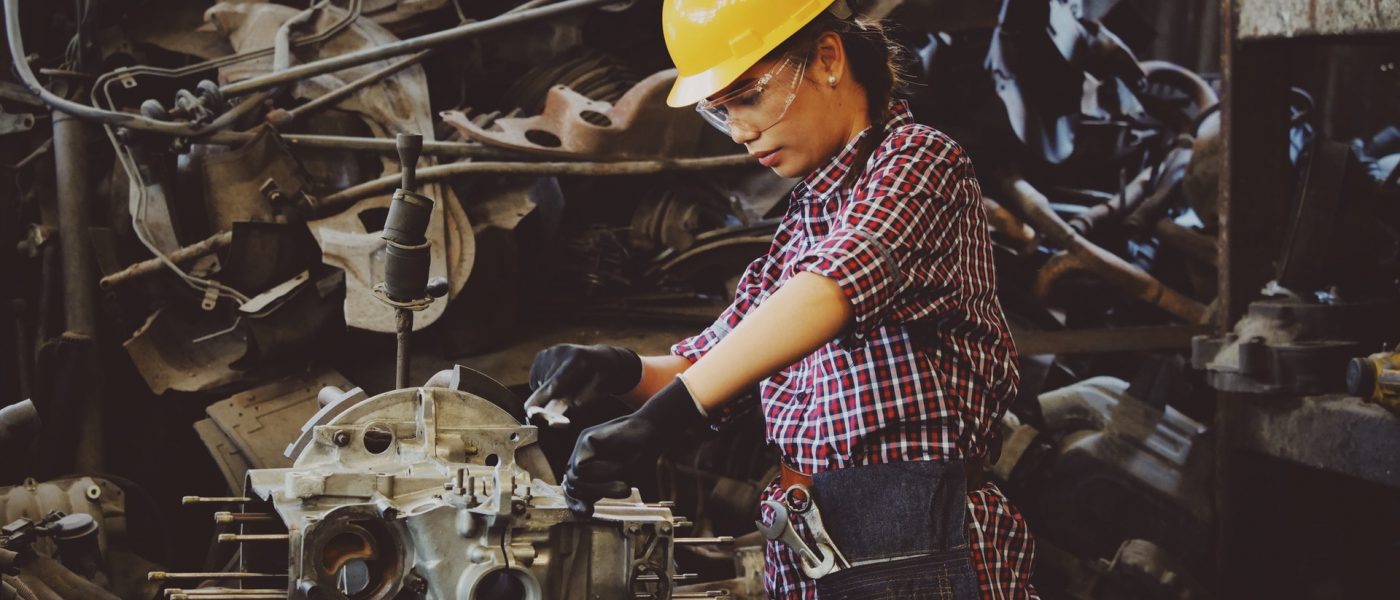 woman engineer working on engine in factory wearing a heard helmet woman engineer working on engine in factory wearing a heard helmet