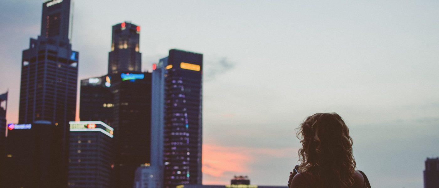 Woman facing financial district Woman stands facing financial district skyscrapers